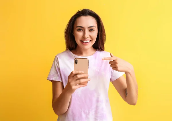 Glimlachende Vrouw Die Wijst Naar Een Mobiele Telefoon Een Gele — Stockfoto