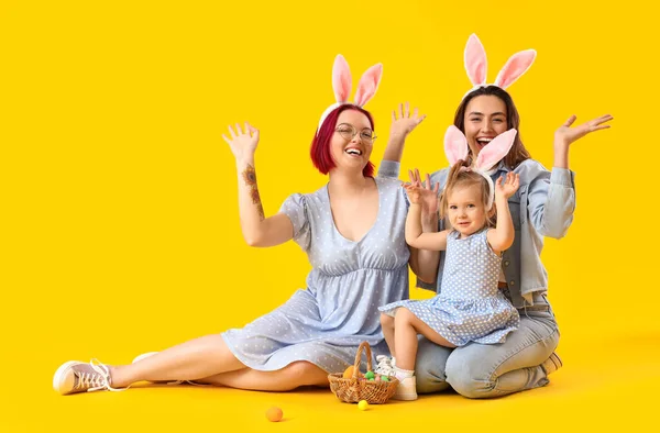 幸せなレズビアンカップルともに小さな娘とイースターの卵上の色の背景 — ストック写真