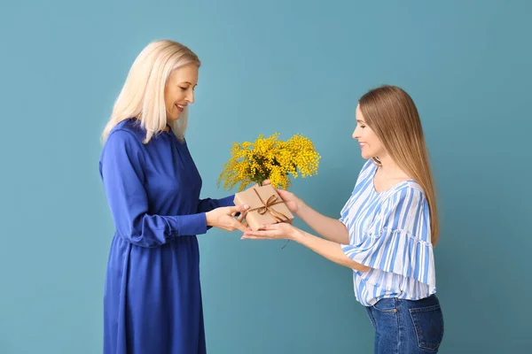 Young Woman Greeting Her Mother Flowers Gift Blue Background — Stock Photo, Image