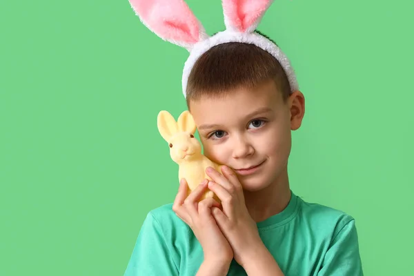 Netter Kleiner Junge Mit Hasenohren Und Spielzeugkaninchen Auf Grünem Hintergrund — Stockfoto