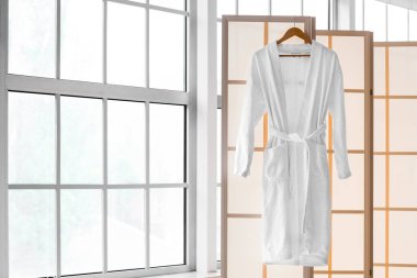 Açık banyoda pencerenin yanındaki bornozlu katlanan ekran.