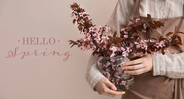 在色彩背景的花瓶里有美丽的开花的树枝的女人 你好春天 — 图库照片