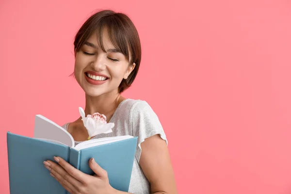 Schöne Junge Frau Mit Buch Und Blume Auf Rosa Hintergrund — Stockfoto