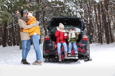 Karlı kış günlerinde ormanda çocuklarını ve arabalarını seven ebeveynler.