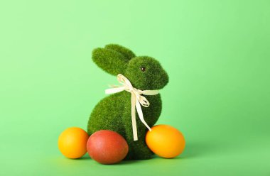 Güzel Paskalya tavşanı ve yeşil arka planda boyanmış yumurtalar.