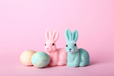 Güzel Paskalya tavşanları ve pembe arka planda boyanmış yumurtalar.