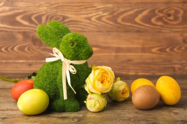 Güzel Paskalya tavşanı, çiçekler ve tahta arka planda boyanmış yumurtalar.