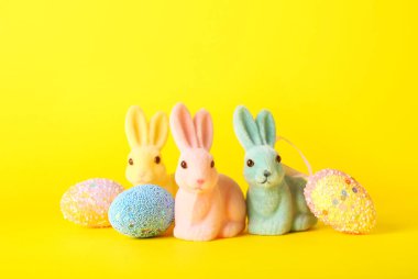 Güzel Paskalya tavşanları ve sarı arka planda boyanmış yumurtalar.