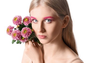 Abartılı makyajlı bir kadının portresi beyaz arka planda güzel çiçekler tutuyor.