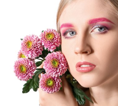 Yaratıcı makyajlı güzel bir kadın beyaz arka planda güzel çiçekler tutuyor.