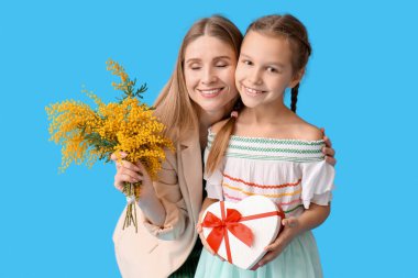 Annesi ve mavi arka planda hediyeleri olan küçük bir kız.