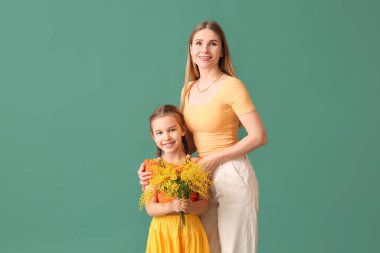 Mimoza çiçekli küçük bir kız ve yeşil arka planda bir anne.