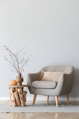 Masada renkli Paskalya yumurtaları ve ışık duvarının yanındaki koltuğu olan ağaç dalları.