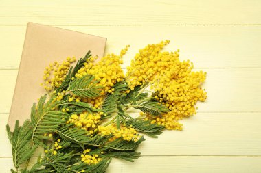 Güzel mimoza dalları ve renkli ahşap zemin üzerine kitap