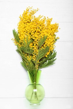 Hafif ahşap arka planda güzel mimoza dalları olan vazo.