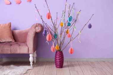 Ağaç dalları olan vazo ve oda duvarının yanında Paskalya dekoru.