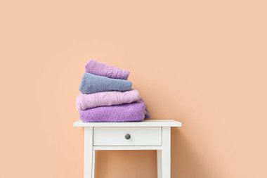 Renkli duvarın yanındaki masada örülmüş süveterler.