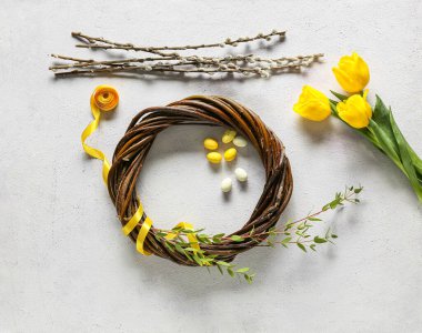 Composition with Easter wreath, tulip flowers, pussy willow branches and ribbon on light background