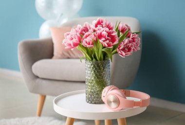 Odadaki masada lale ve kulaklıklı vazo.