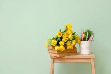 Lale buketi, kitap yığını ve renkli duvarın yanındaki merdivende Paskalya dekoru.