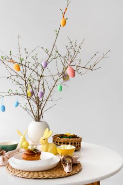 Ağaç dalları olan vazo ve yemek masasında Paskalya kutlaması için servis edilen güzel bir dekor.