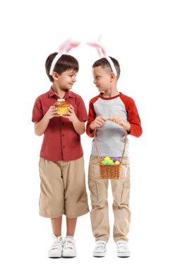 Tavşan kulaklı şirin çocuklar Paskalya sepeti ve beyaz arka planda pasta.