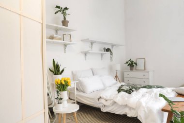 Işıl ışıl yatak odasının içinde vazoda laleler ve bitkiler var.