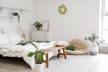 Paskalya çelengi ve bitkilerle aydınlık yatak odasının içinde.