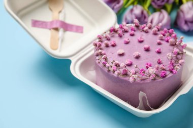 Mavi arka planda lezzetli bento keki olan plastik beslenme çantası, yakın plan.
