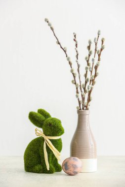 Green Easter bunny, egg and vase with pussy willow branches on light background