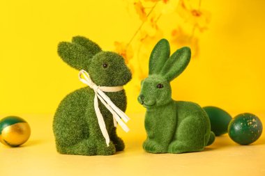Sarı arka planda yeşil Paskalya tavşanları ve yumurtalar