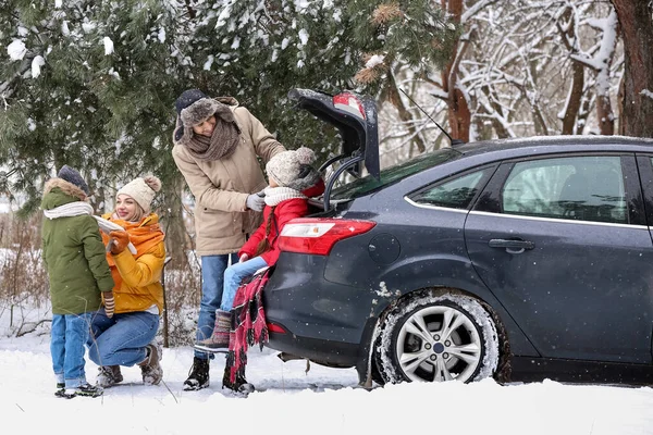 冬の雪の日に車のトランクに座っている幸せな両親とその小さな子供たち — ストック写真
