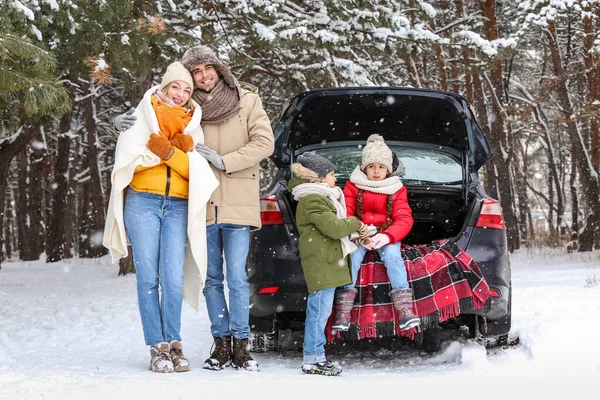 冬の雪の日に森の中で車の近くで熱いお茶を飲む魔法瓶付きの幸せな家族 — ストック写真
