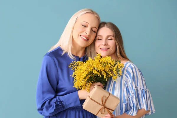 Jonge Vrouw Met Haar Moeder Cadeau Bloemen Blauwe Achtergrond — Stockfoto