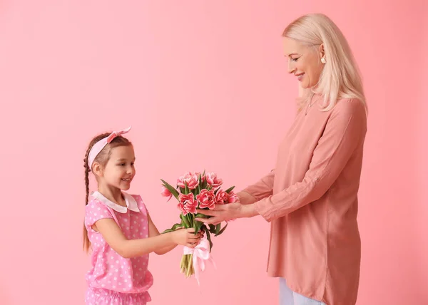 小女孩用粉色背景的花朵和礼物向她的祖母致意 国际妇女日 — 图库照片