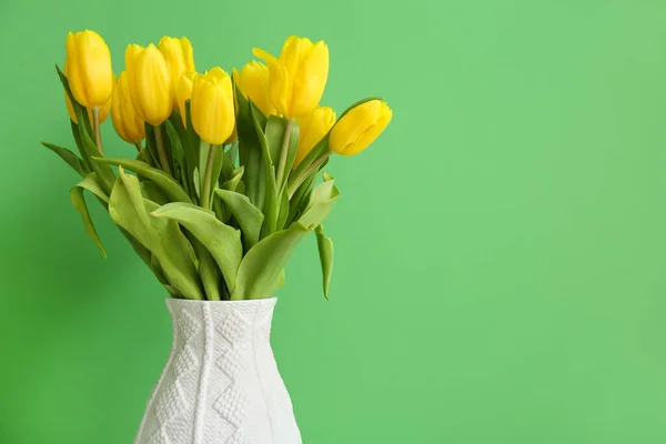 Vase with tulips on color background