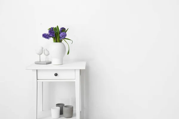 白い壁の近くに立って机の上に花やスタイリッシュな装飾が施された花瓶 — ストック写真