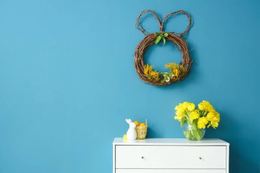 Lale buketi ve renkli duvarın yanındaki çekmecelerin üstündeki Paskalya dekoru.