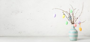 Vazodaki ağaç dallarında sallanan Paskalya yumurtaları hafif arkaplan ve metin için yer var.