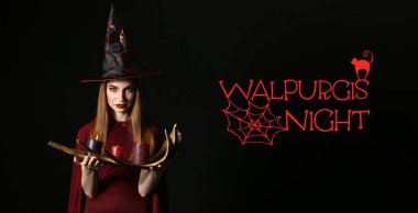 Mumları yakan ve WALPURGIS gecesini siyah arkaplanda yazan genç cadı.