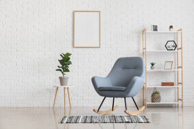Sallanan sandalye, ev bitkisi ve raflar modern oturma odasının içinde.