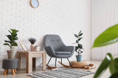 Sallanan sandalye, masa ve ev bitkileriyle oturma odasının içinde.