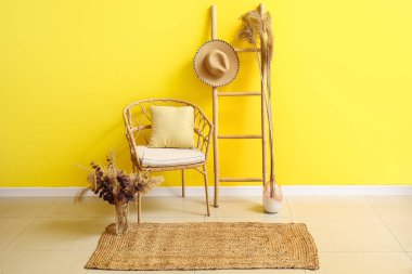 Hasır sandalyesi, merdiveni ve renkli duvarın yanında şık halısı olan bir oda.