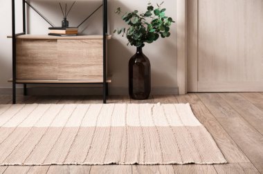 Ayakta duran masa, okaliptüs dallı vazo ve aydınlık odada şık bir halı.