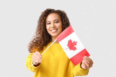Açık arkaplanda Kanada bayrağı olan güzel Afro-Amerikalı kadın.
