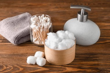 Ahşap arka planda pamuklu banyo malzemeleri.