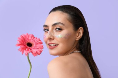 Yaratıcı makyajlı genç bir kadın ve Gerbera çiçeği.