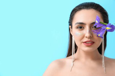 Yaratıcı makyajlı bir kadın ve mavi arka planda bir iris çiçeği.