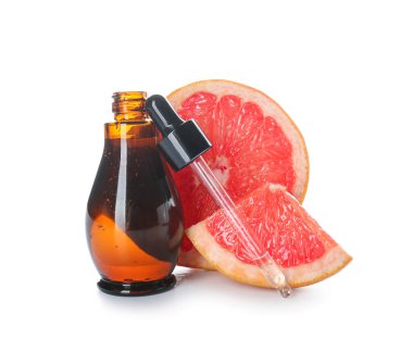 Bir şişe greyfurt yağı ve beyaz arka planda damlalar.