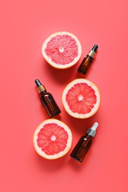Renkli arka planda gerekli yağ şişeleri ve olgun greyfurtlarla kompozisyon